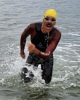 Craig running out of the water, in a wetsuit