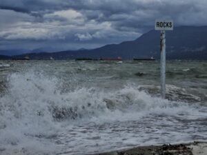 Waves crashing on to kits beach with the Rocks sign as a warning